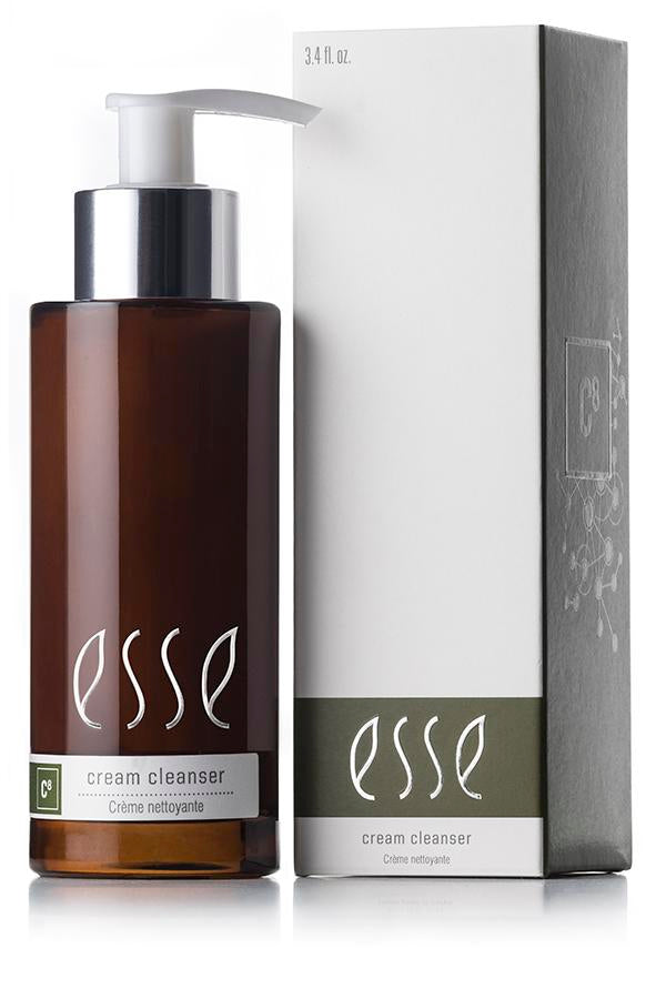 En 200 ml brun pumpeflaske med Esse Cream Cleanser fra Hudkonsulenten Monrad-Krohn står ved siden av den matchende esken, begge med "esse" i små bokstaver og produktnavnet under.